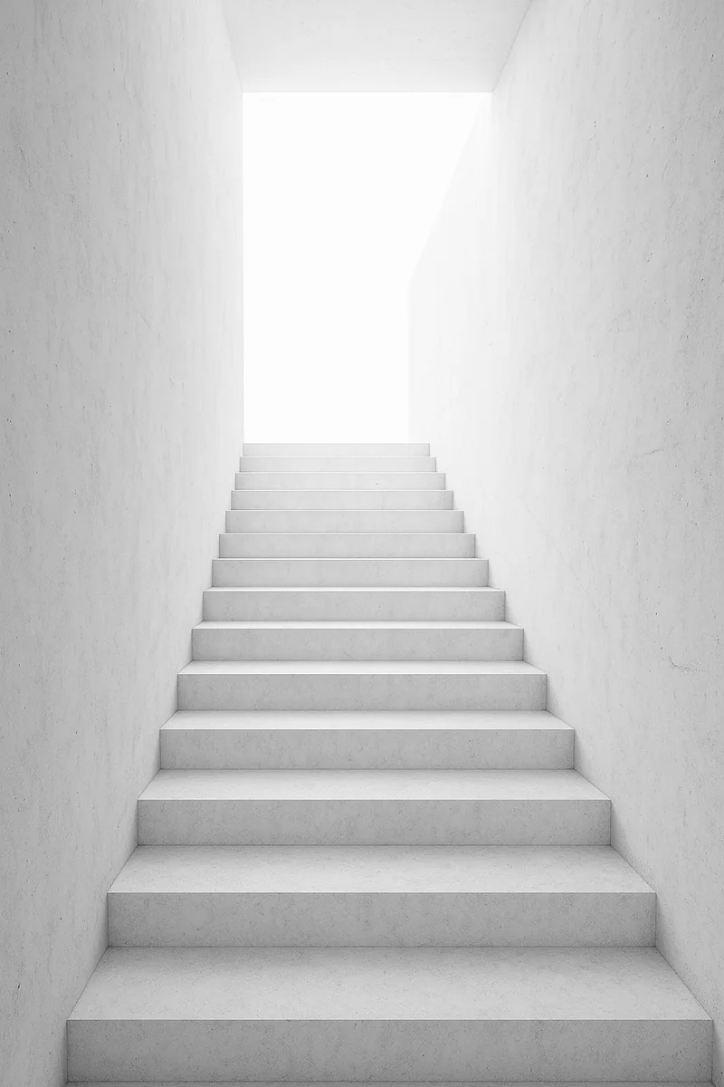Escalera de hormigón blanco que sube hacia la luz